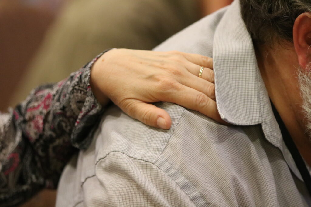 A person comforting another, by placing their hand on the person's shoulder