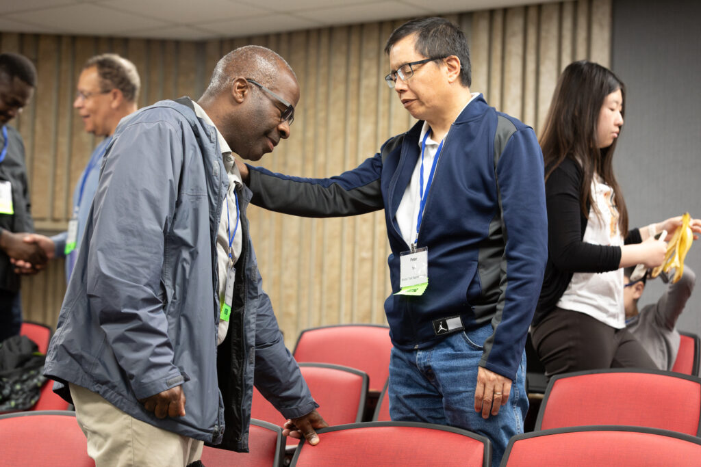 Man consoles another with a hand on shoulder in a conference room.