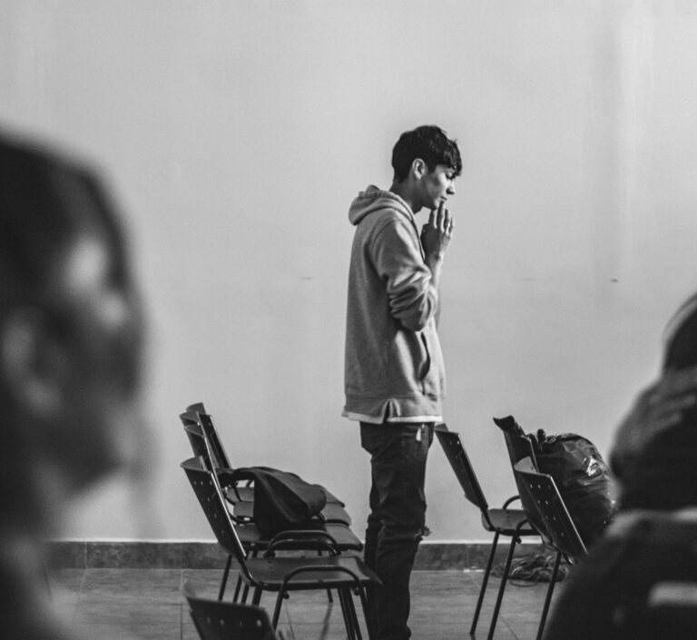 Black and white photo of a young person standing, hands clasped, in prayer.