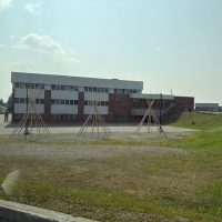 Brick school with three wooden teepee frames on a sunny day